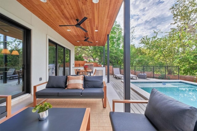 exterior space featuring outdoor lounge area, a swimming pool side deck, ceiling fan, and exterior kitchen