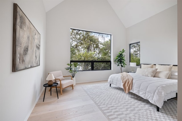 bedroom featuring light wood-type flooring and high vaulted ceiling