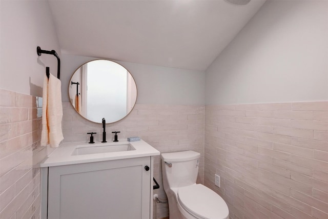 bathroom with vanity, toilet, tile walls, and vaulted ceiling