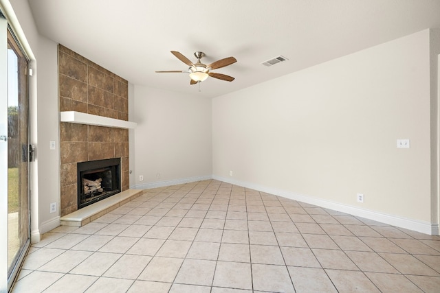 unfurnished living room with ceiling fan, a fireplace, and light tile patterned flooring