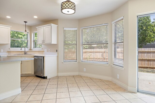 kitchen featuring pendant lighting, white cabinets, sink, stainless steel dishwasher, and light tile patterned floors