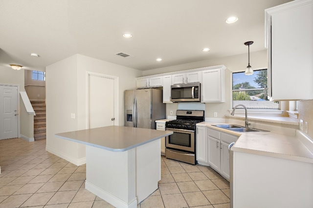 kitchen with appliances with stainless steel finishes, sink, pendant lighting, a center island, and white cabinetry