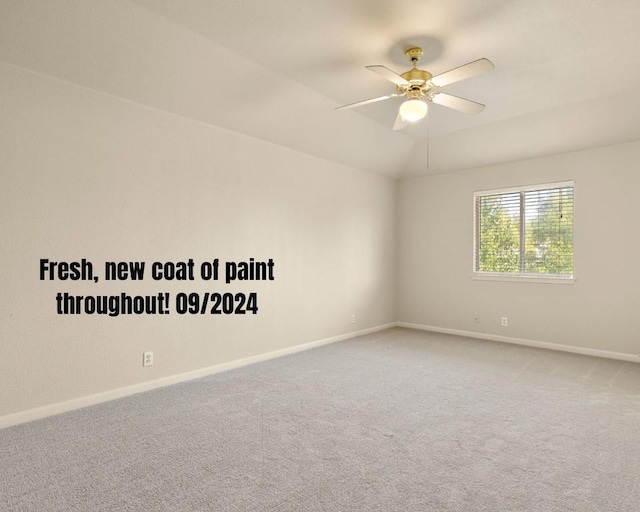 unfurnished room with carpet flooring, a ceiling fan, baseboards, and vaulted ceiling