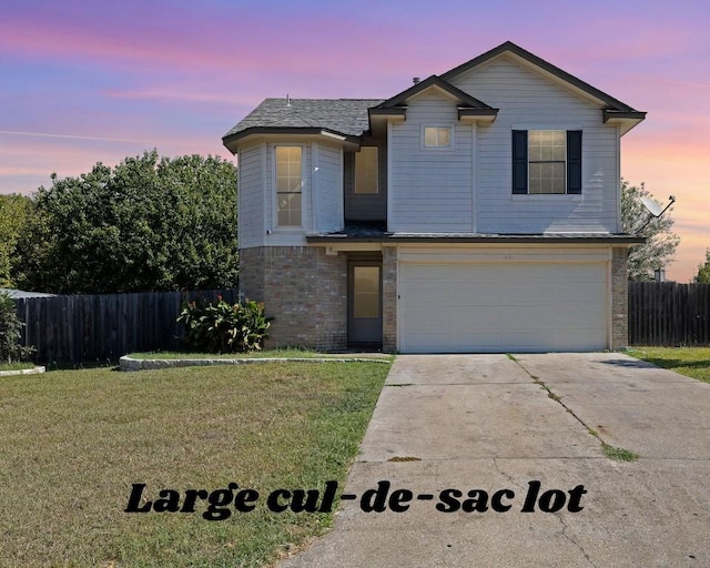 traditional home with driveway, fence, a front yard, an attached garage, and brick siding