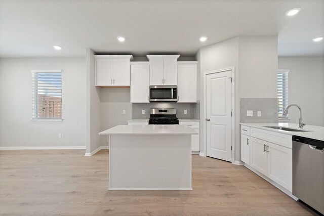 kitchen with stainless steel appliances, white cabinetry, light hardwood / wood-style floors, and sink