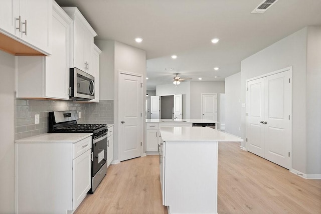 kitchen featuring white cabinetry, light hardwood / wood-style flooring, a kitchen island, and stainless steel appliances