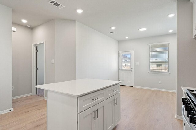 kitchen featuring light hardwood / wood-style floors, a center island, white cabinetry, and white gas range oven