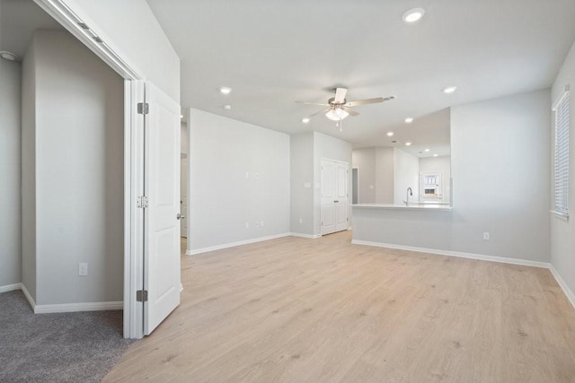 unfurnished living room with ceiling fan, light hardwood / wood-style floors, and sink