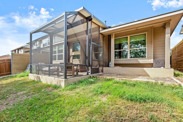 rear view of property featuring a patio, a yard, and a lanai