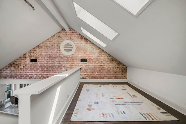 additional living space featuring dark wood finished floors, brick wall, baseboards, and lofted ceiling with skylight