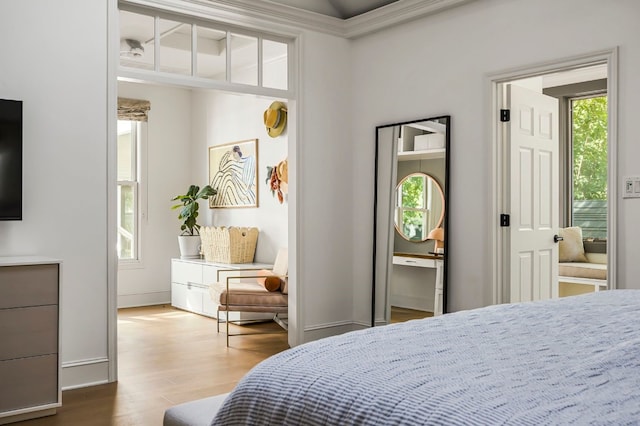 bedroom with baseboards, crown molding, wood finished floors, and multiple windows