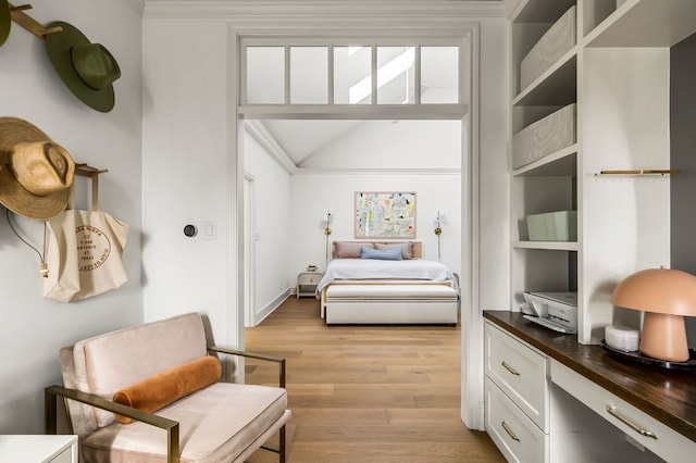 bedroom featuring light wood-type flooring, lofted ceiling, and crown molding