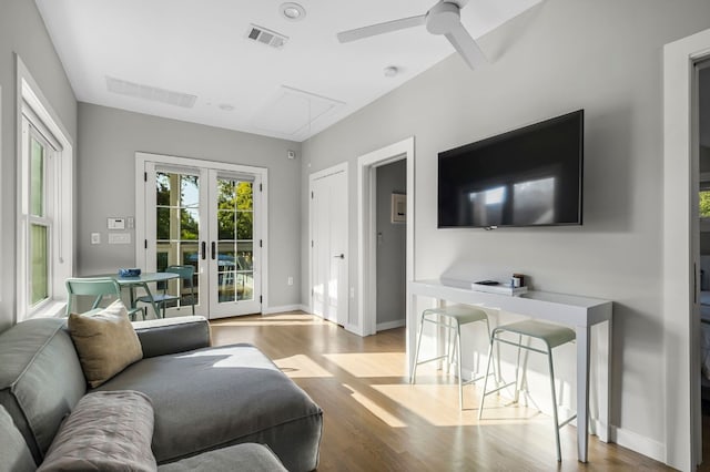 living area featuring attic access, french doors, visible vents, wood finished floors, and ceiling fan