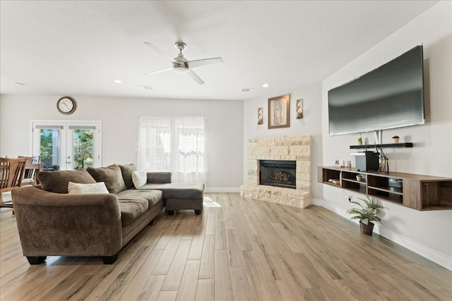 living room featuring a fireplace, light wood-type flooring, and ceiling fan