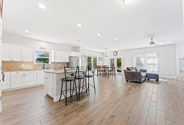 kitchen featuring stainless steel refrigerator, white cabinetry, a center island, and light hardwood / wood-style flooring