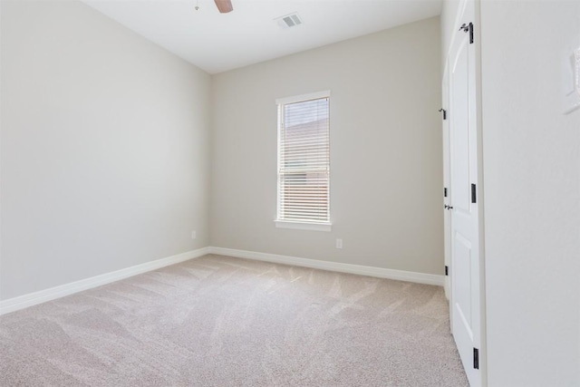 empty room featuring baseboards, ceiling fan, visible vents, and light colored carpet