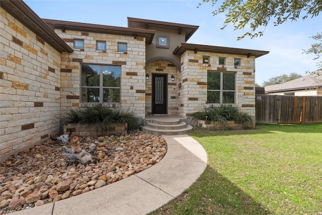 view of front facade with stone siding, fence, and a front yard