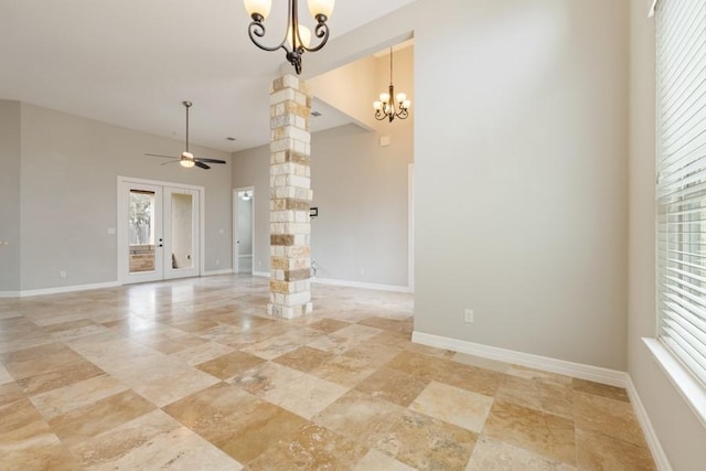 empty room with baseboards, ceiling fan with notable chandelier, and ornate columns