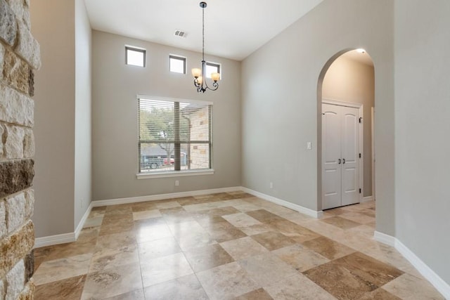 spare room featuring a towering ceiling, baseboards, visible vents, and arched walkways