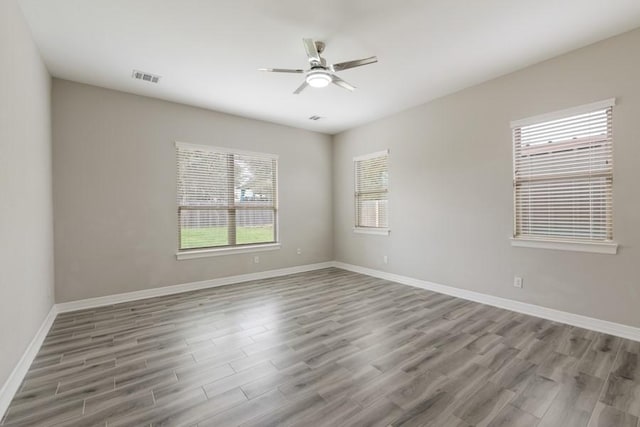 unfurnished room with baseboards, wood finished floors, visible vents, and a ceiling fan