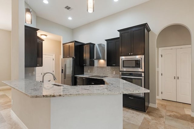 kitchen featuring visible vents, appliances with stainless steel finishes, a sink, light stone countertops, and wall chimney exhaust hood