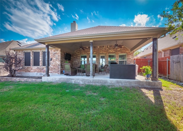 back of property with a yard, ceiling fan, and a patio area