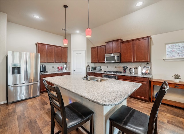 kitchen featuring pendant lighting, dark hardwood / wood-style floors, sink, an island with sink, and stainless steel appliances