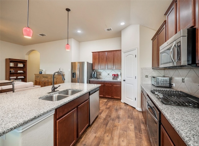 kitchen featuring hanging light fixtures, sink, appliances with stainless steel finishes, light stone countertops, and dark hardwood / wood-style flooring