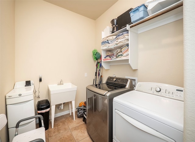 laundry area with light tile patterned floors, washer and clothes dryer, and sink