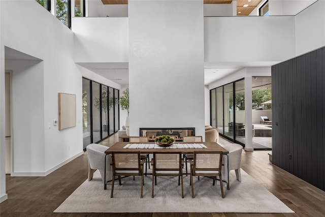 dining area featuring a towering ceiling, a wealth of natural light, and wood-type flooring