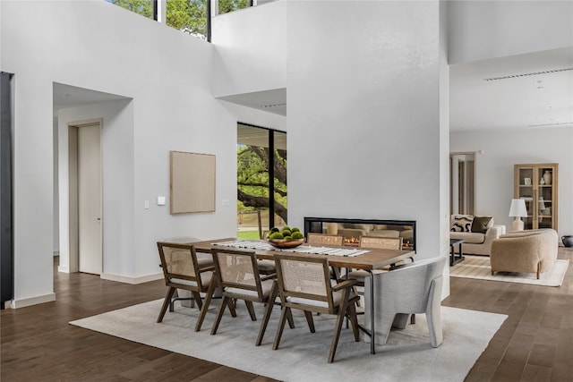 dining area with a high ceiling, dark hardwood / wood-style floors, and a wealth of natural light