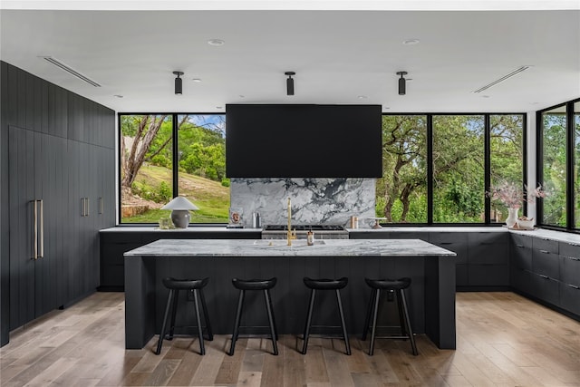 kitchen featuring a center island with sink, a kitchen breakfast bar, and a healthy amount of sunlight