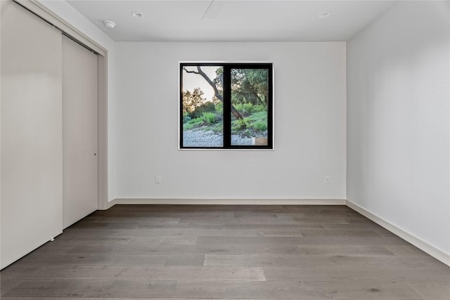 2400 Trail Of The Madrones, Austin, TX 78746 - unfurnished bedroom with wood finished floors, a closet, recessed lighting, and baseboards