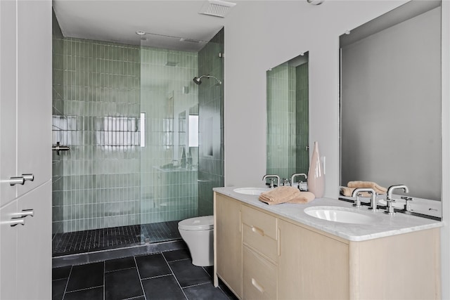 bathroom with a tile shower, vanity, toilet, and tile patterned floors