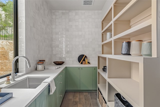 kitchen featuring backsplash, green cabinetry, sink, and dark wood-type flooring