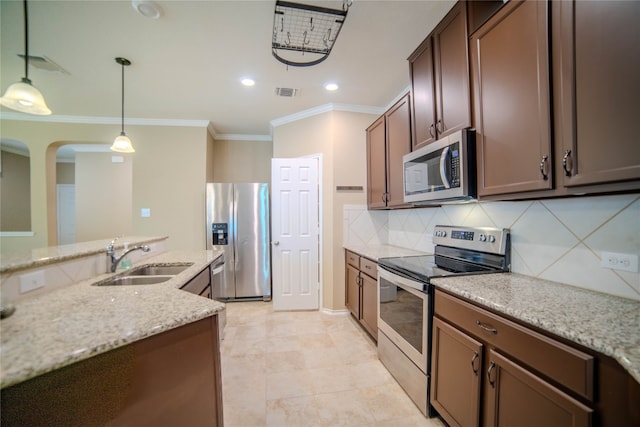 kitchen featuring appliances with stainless steel finishes, light stone counters, tasteful backsplash, pendant lighting, and sink