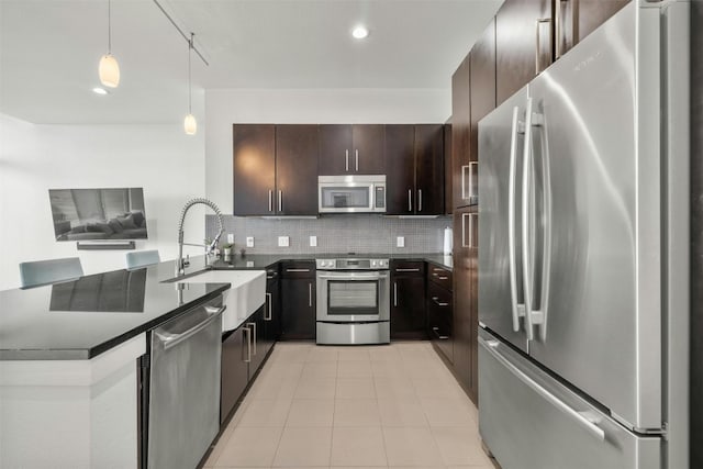 kitchen with dark countertops, tasteful backsplash, appliances with stainless steel finishes, and a sink