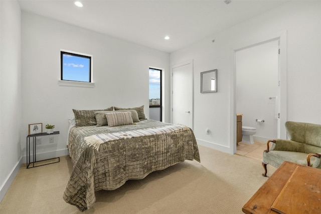 bedroom featuring ensuite bath and light colored carpet