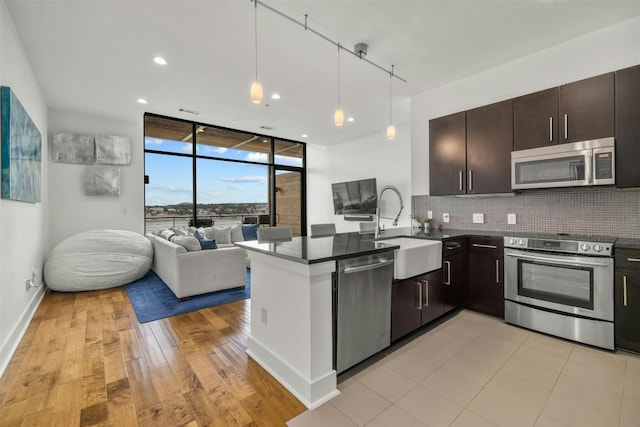 kitchen featuring stainless steel appliances, expansive windows, backsplash, and dark countertops