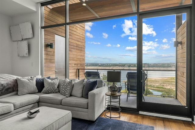 living area featuring a healthy amount of sunlight, floor to ceiling windows, a water view, and wood finished floors