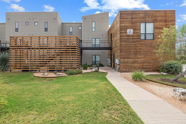 back of property with a yard and a balcony