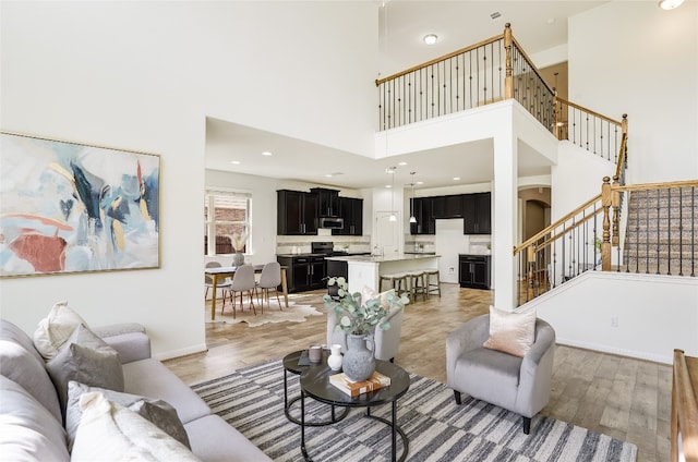 living room featuring sink, wood-type flooring, and a towering ceiling