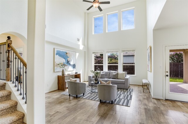 living room featuring a wealth of natural light, a towering ceiling, ceiling fan, and light hardwood / wood-style flooring