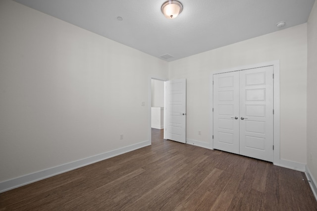 unfurnished bedroom with a closet and dark wood-type flooring