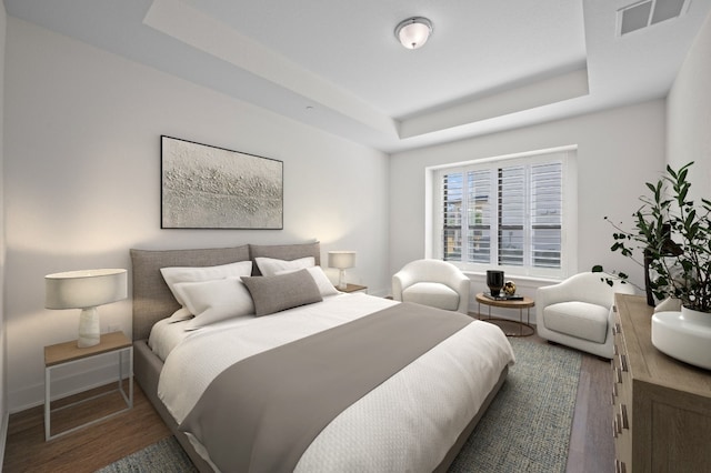 bedroom with wood-type flooring and a raised ceiling