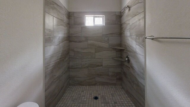 bathroom featuring toilet and a tile shower