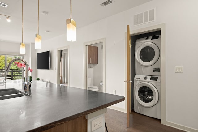 washroom with sink, dark wood-type flooring, and stacked washer and dryer