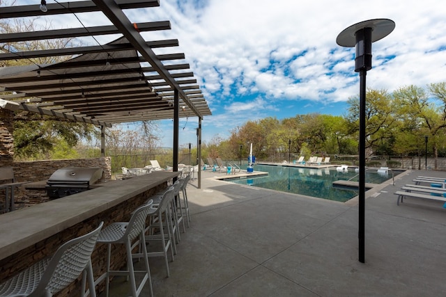 view of swimming pool with an outdoor bar, a pergola, a patio, and grilling area