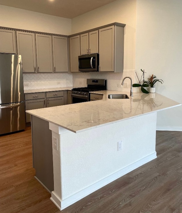 kitchen with stainless steel appliances, kitchen peninsula, dark wood-type flooring, and sink