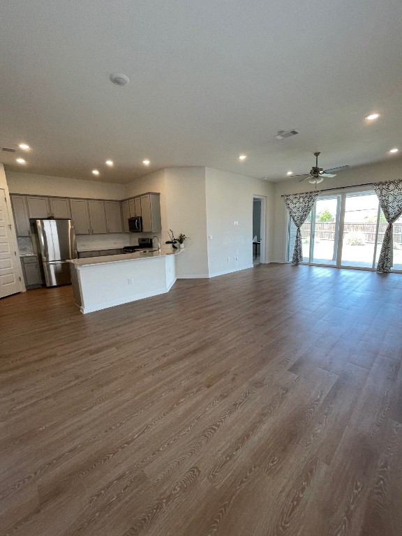 unfurnished living room with dark hardwood / wood-style floors and ceiling fan